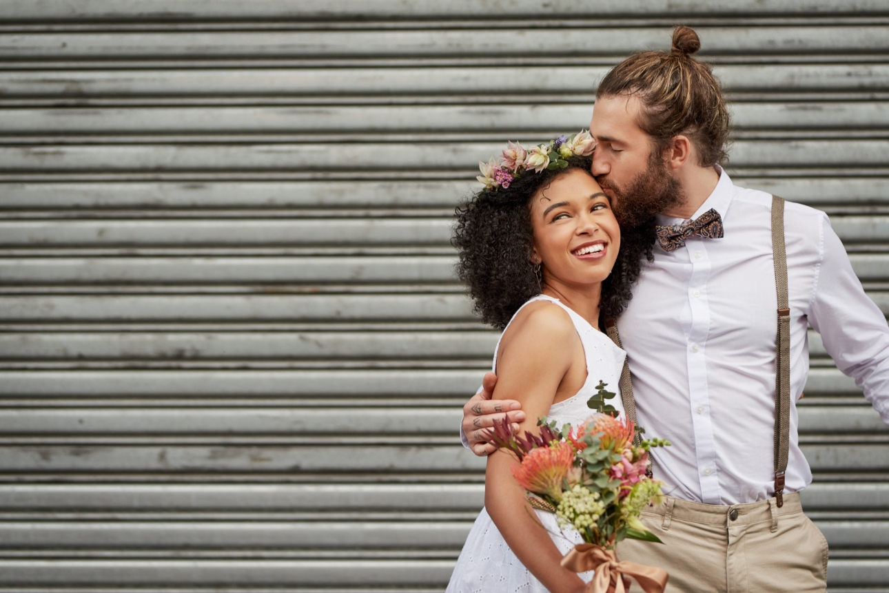 Groom kisses bride in front of industrial roller door