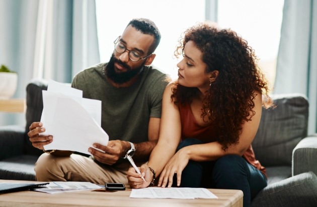 Couple sit on sofa doing paperwork on coffee table