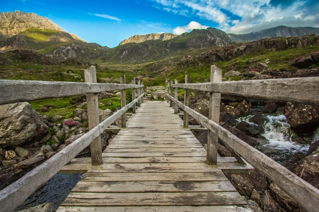 wooden bridge pointing to hills