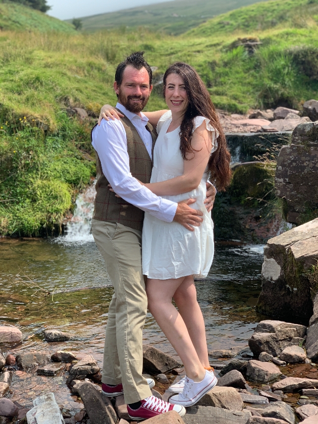 Couple embrace in front of waterfall