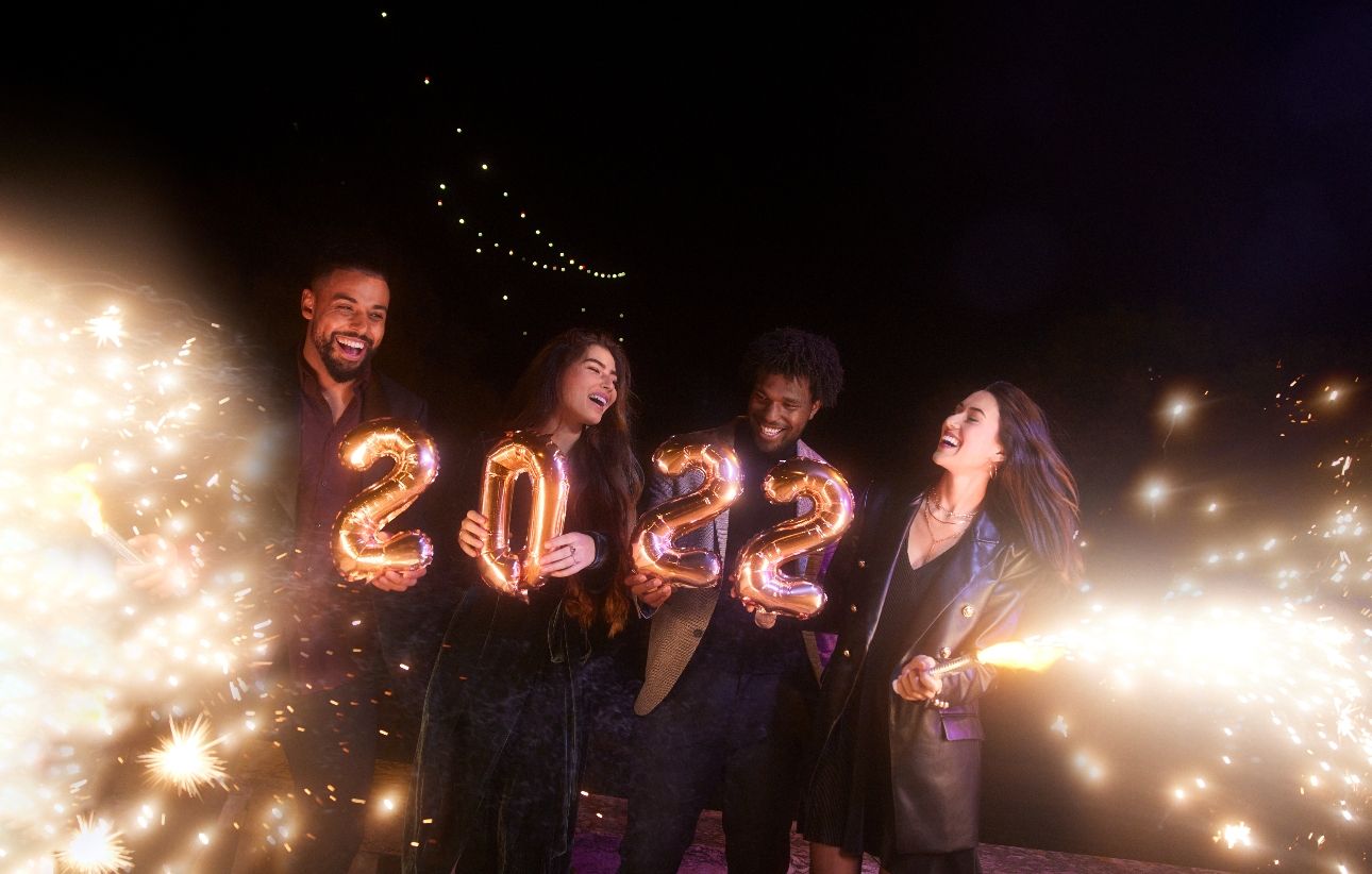 four friends at night holding 2022 balloons and sparklers