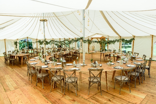 Inside a marquee with round tables dressed with flowers