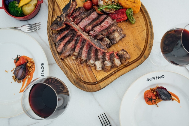 board of meat with two plates and two red wines