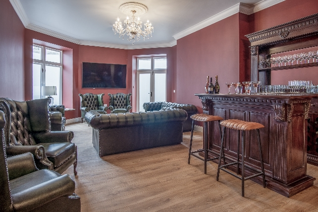 historic drawing room with red walls, chesterton leather sofas and wooden bar are