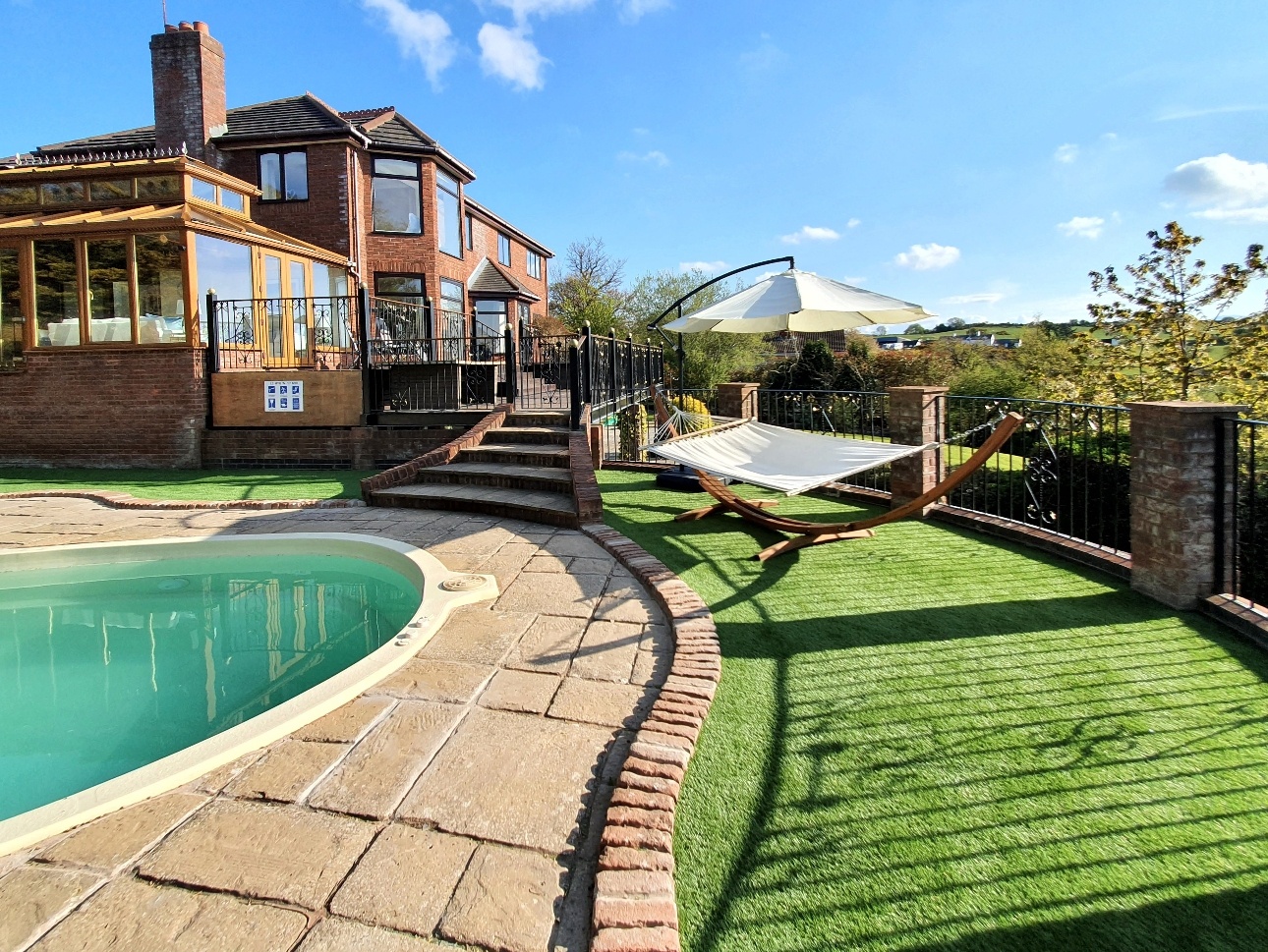 large house red brick house, with heated pool faux grass and sungloungers and canopies