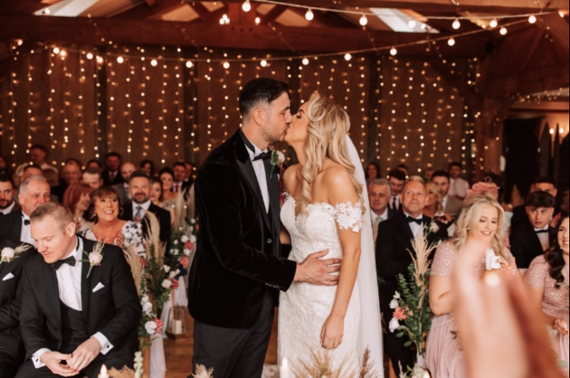 Bride and groom kissing at the aisle surrounded by friends and family