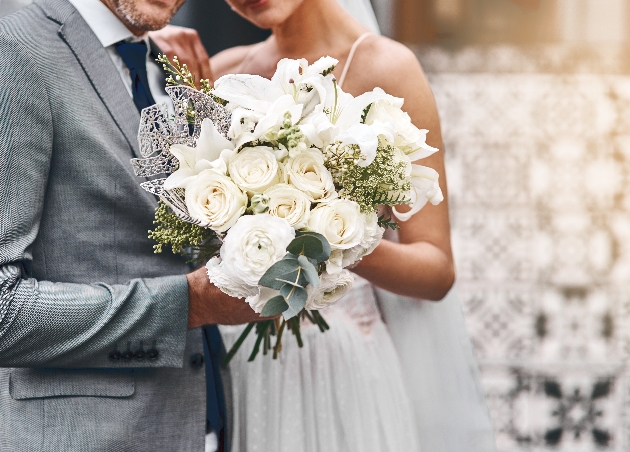 Close up of a bride and groom holding a wedding bouquet