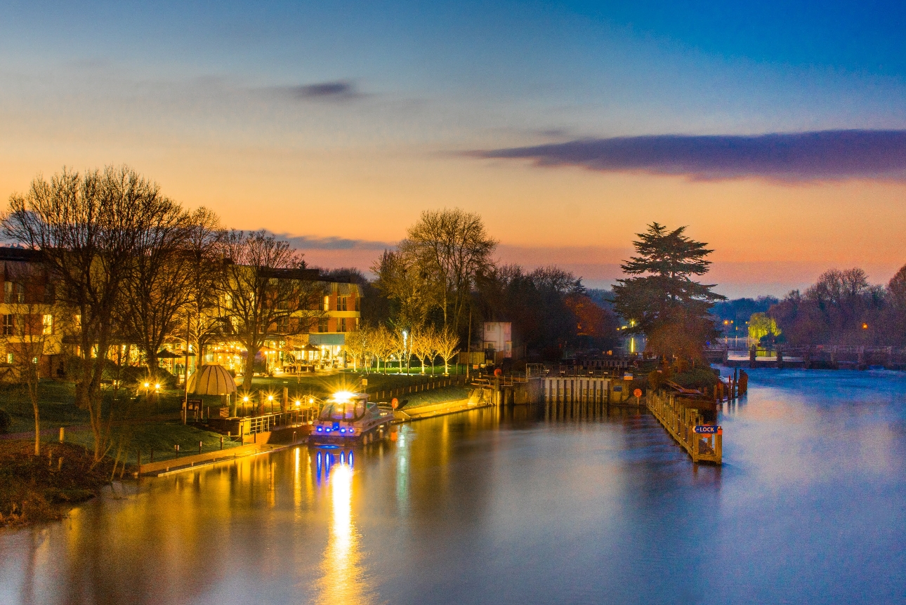 riverside hotel at night with boat dock and outside terrace area next to river