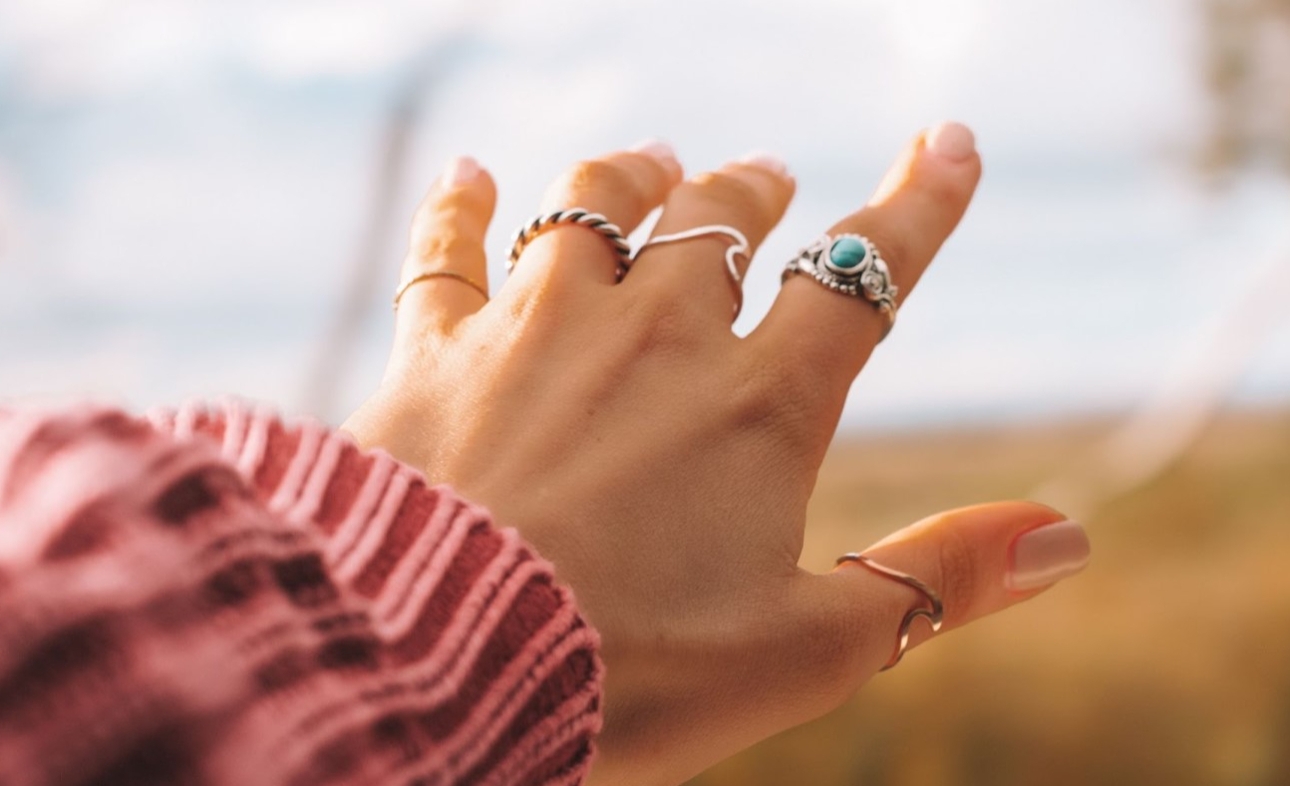 hand with pink jumper and lots of silver rings