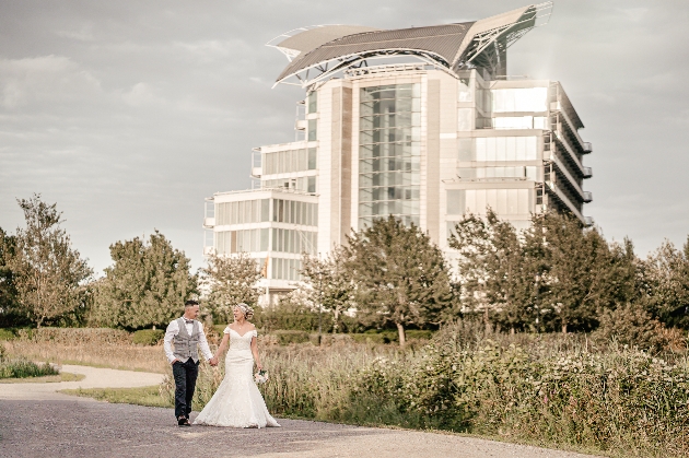 Bride and groom walking in front of Voco St. David’s, Cardiff