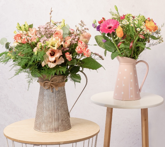 two rustic milk jugs with large bouquets in