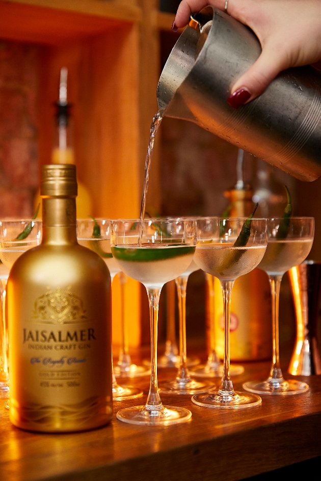 gold bottle of gin cocktails glasses on a bar