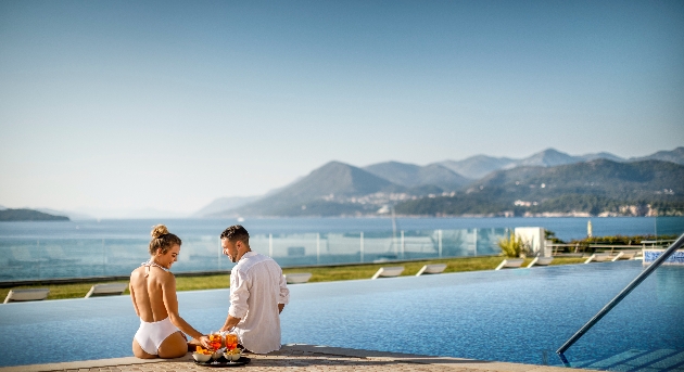 A couple sitting next to a swimming pool