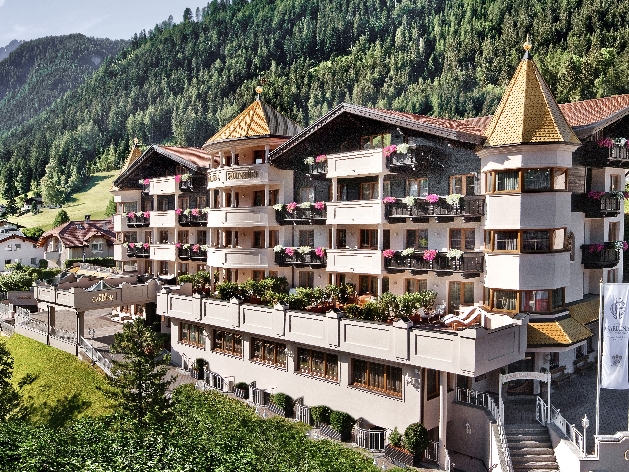 A white building with gold accents on the roof surrounded by mountains