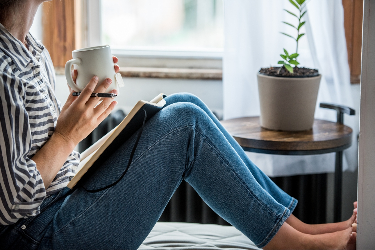 woman looking out window writing in book