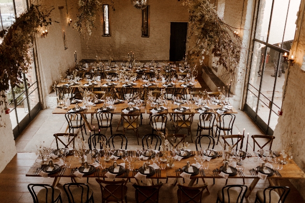 Rows of wooden tables decorated with flowers in a stone barn