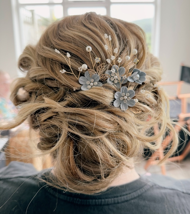 The back of a bride's head showing her hair curled with a flower clip added