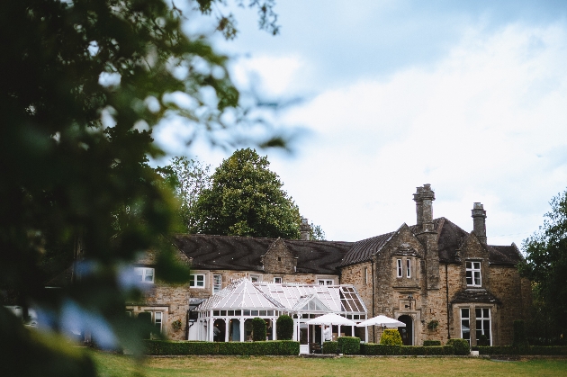 The exterior of a manor house with a white conservatory attached