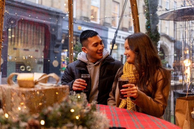 Man and woman drinking in front of a Christmas present