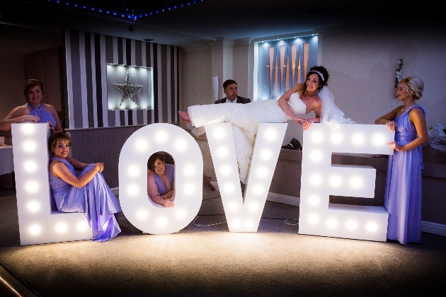 A woman and her bridesmaids lying on top of giant love letters