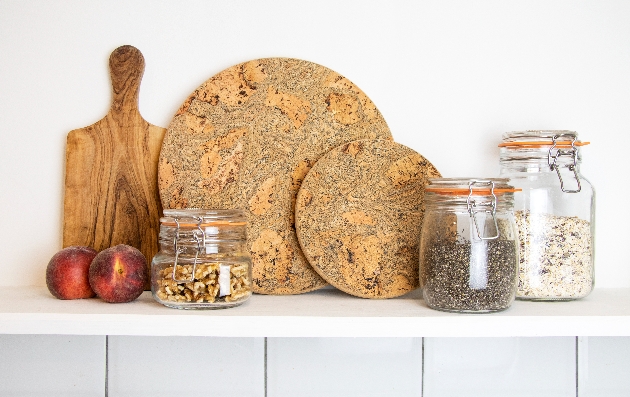 Two apples, two place mats, three jars and a chopping board on a sideboard