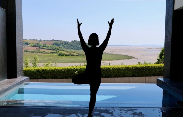 A woman doing yoga in front of a swimming pool