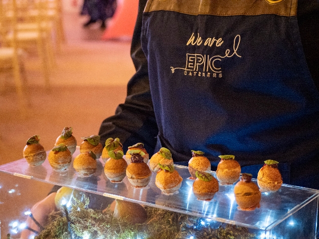 A person in an apron holding canapés on a tray
