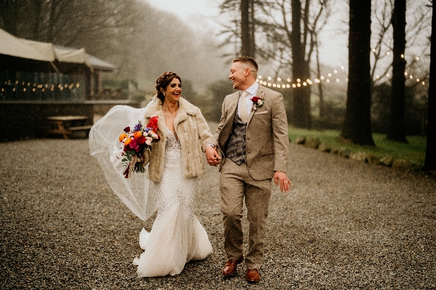 A bride and groom walking hand-in-hand laughing