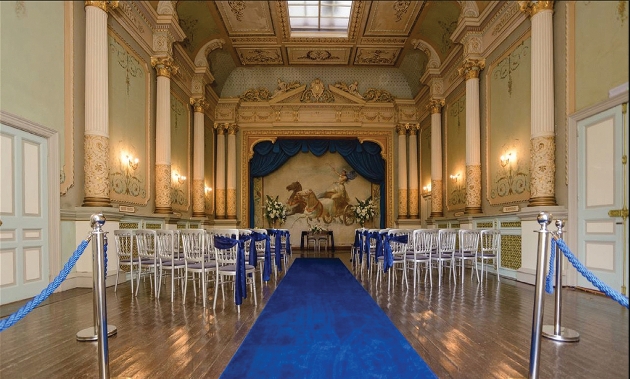 A grand room with columns and a painting at the end of the room