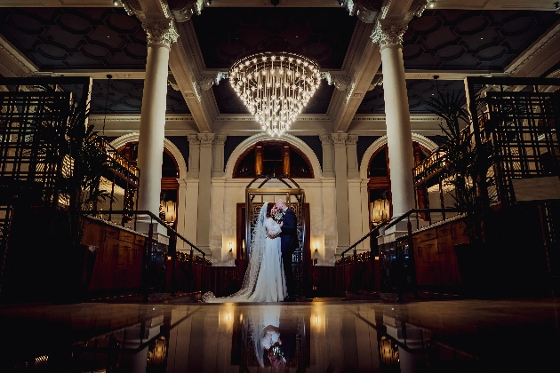 A bride and groom standing underneath a chandelier