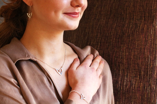 A woman wearing a heart-shaped necklace, earrings and a bracelet