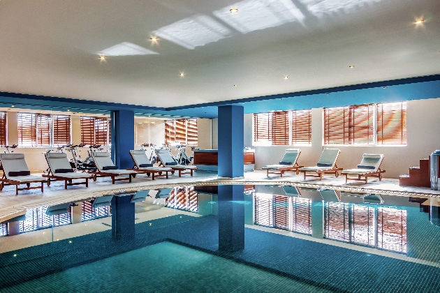 An indoor swimming pool with chairs around the sides