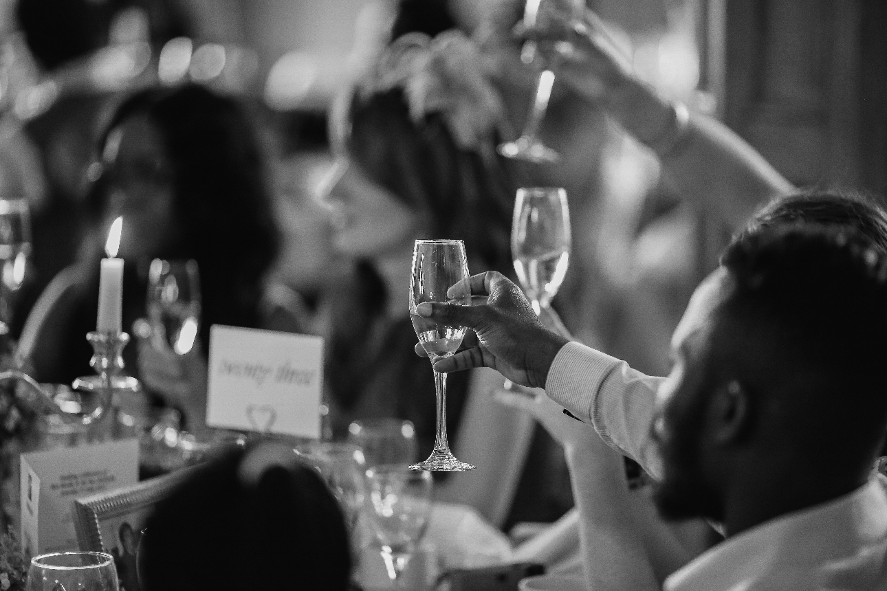 black and white photo of guests raising a toast at a wedding reception