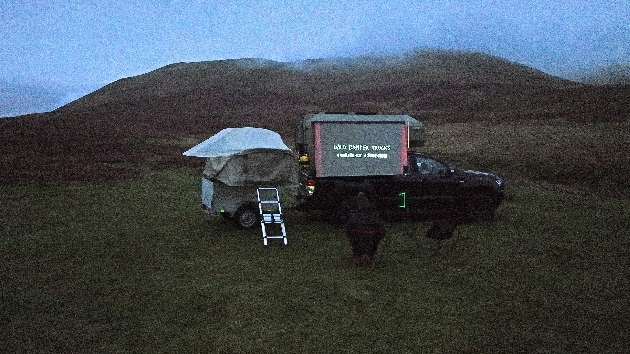 A truck at night with a cinema projector in the side