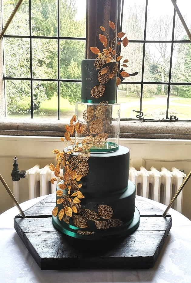 A dark blue wedding cake decorated with gold leaves