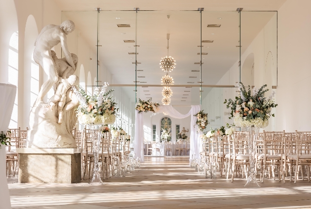 A light room decorated with flowers, statues and chairs