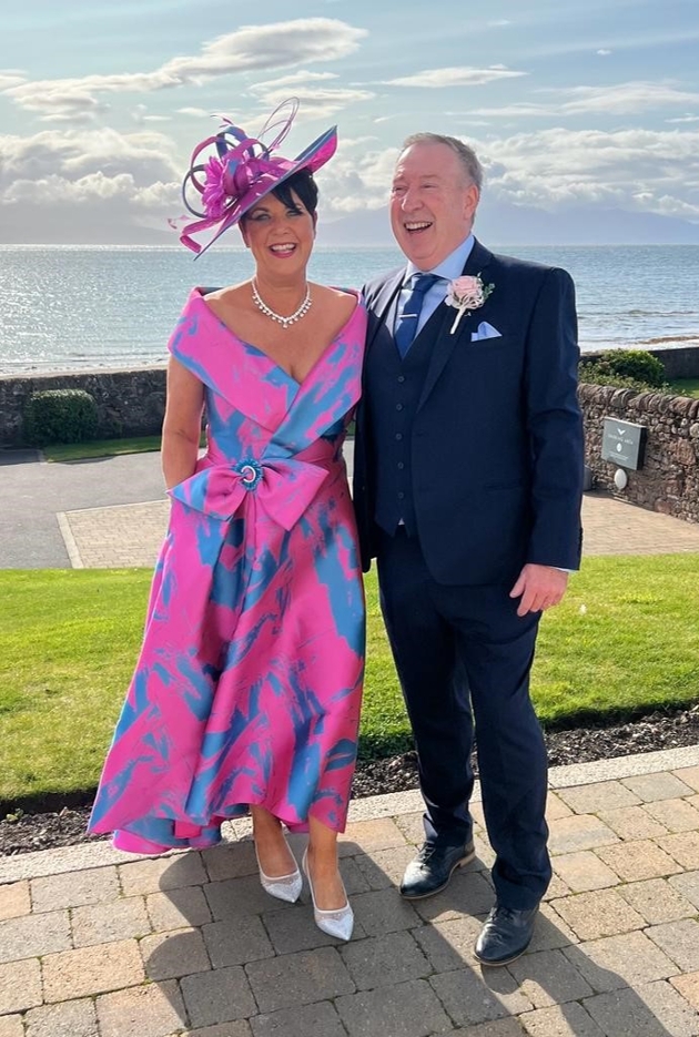 woman in pink and blue outfit for wedding with hat