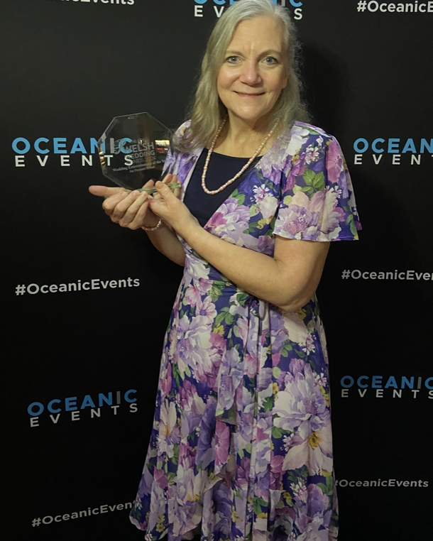 A lady in a floral dress holding an award