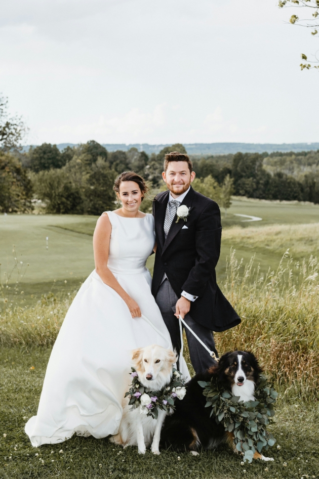 bride and groom with their dogs on a field