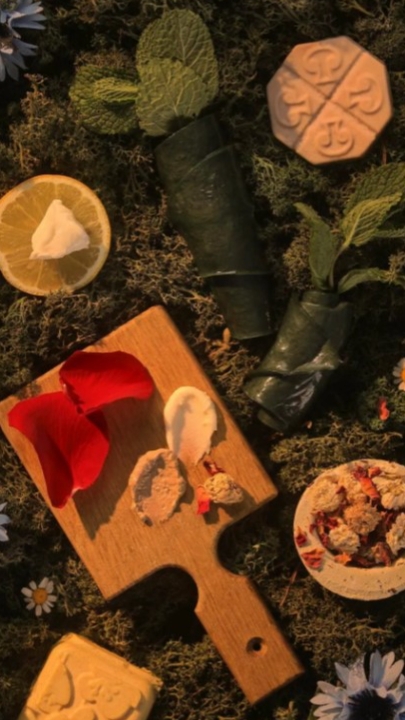 skincare on chopping board with greenery and rose petals