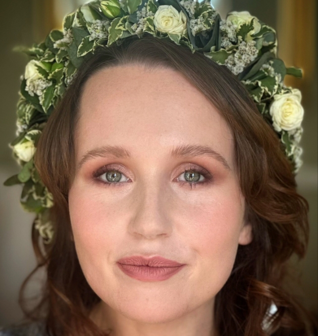 a woman with brown hair and flower crown looking at the camera