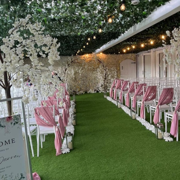 grassy aisle with pink and white chairs either side