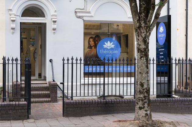 The exterior of a white building with a Thérapie Clinic sign in the window