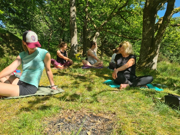 A group of women sitting on mats in the forest
