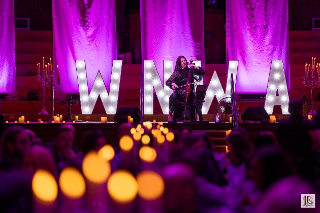 A woman playing an instrument in front of light-up letters