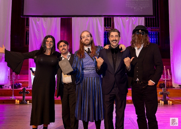 Four people smiling at the camera with an award