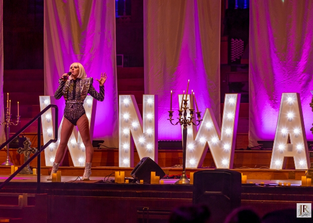 A woman singing in front of light-up letters