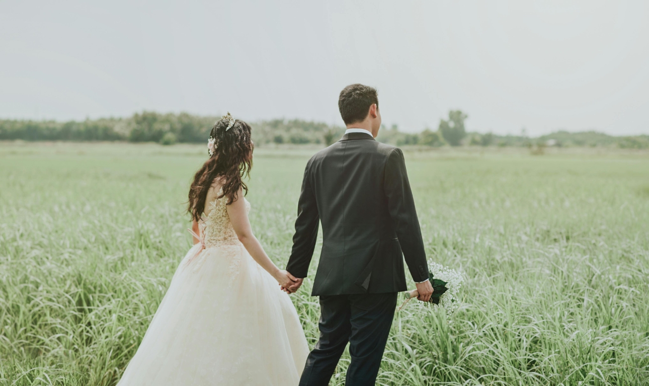 bride and groom walking across a field