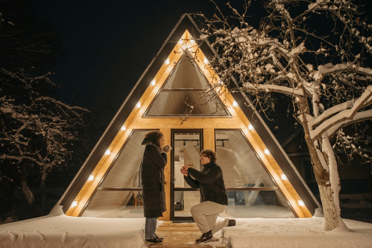 man proposing to woman out side a holiday lodge in the snow
