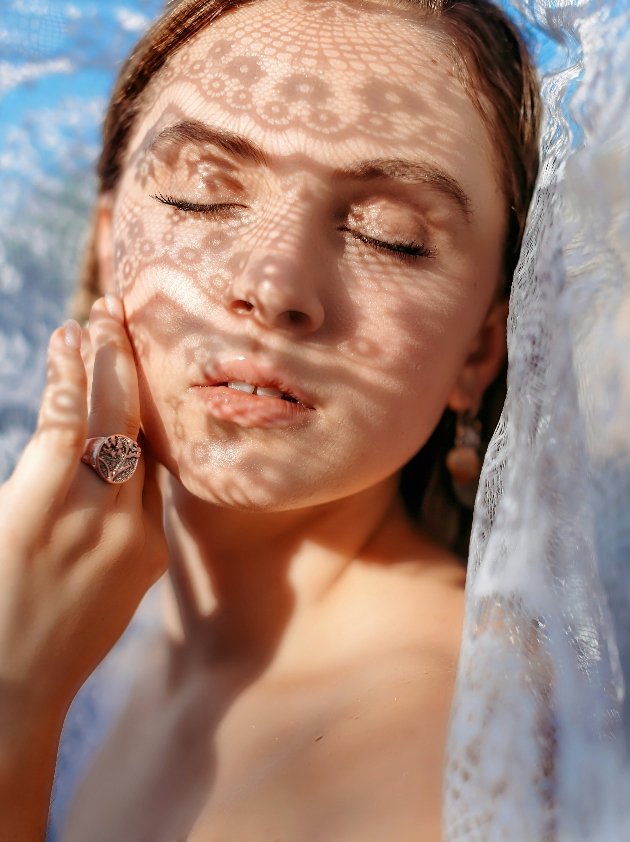 A woman in a veil closing her eyes and posing for the camera